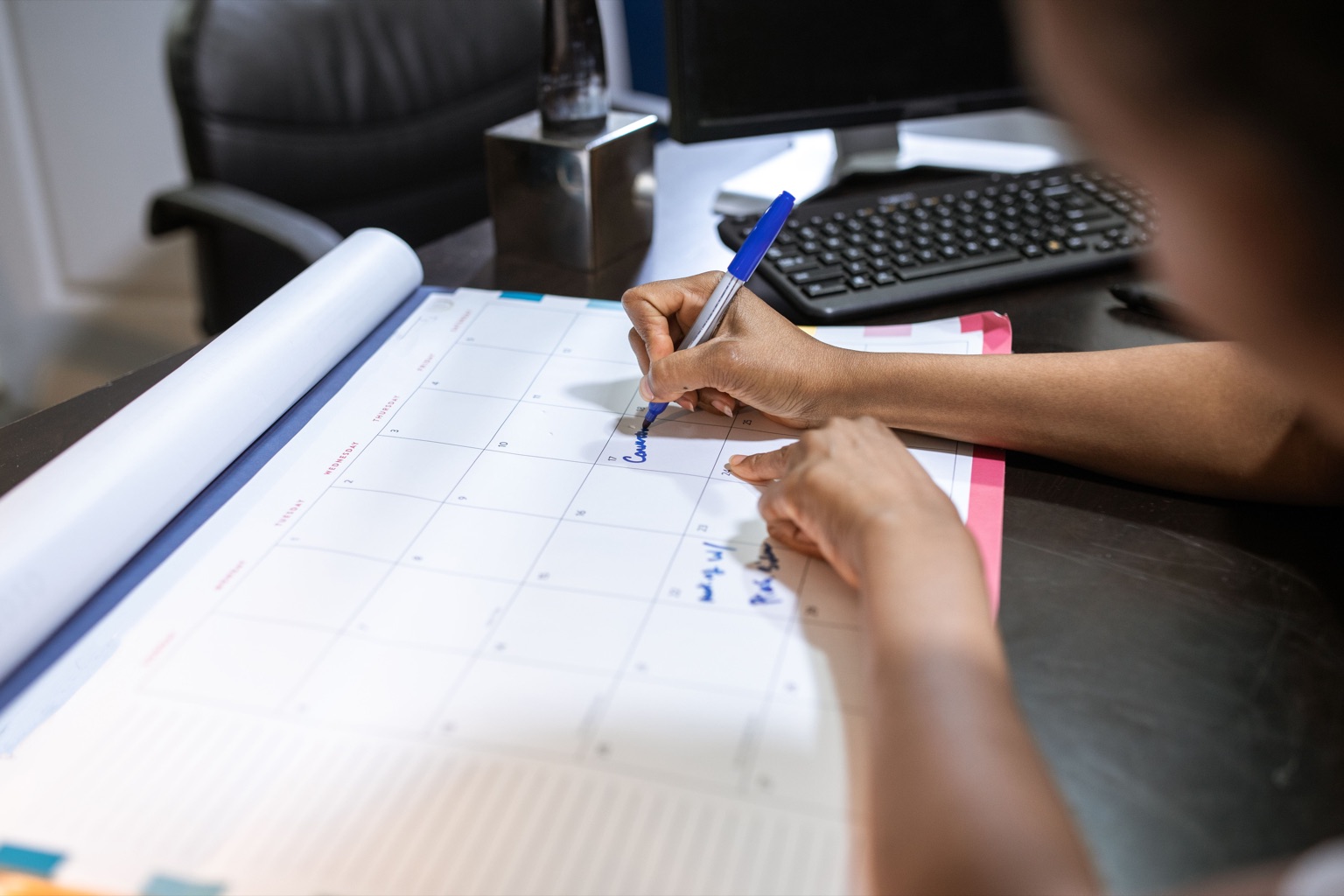 Employee writing approved time off on a desk calendar